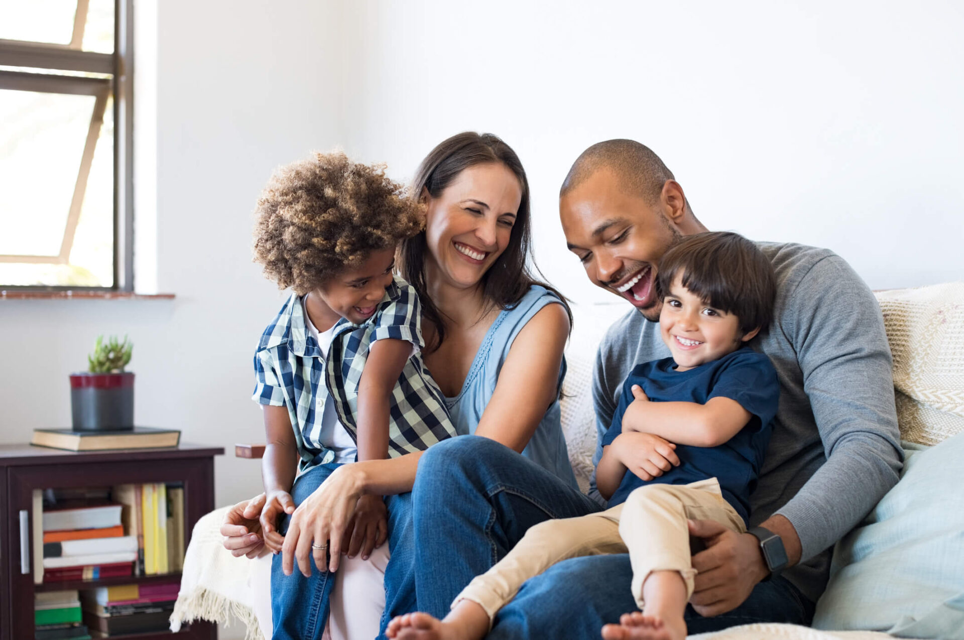 foster family of four sitting on couch laughing joyfully